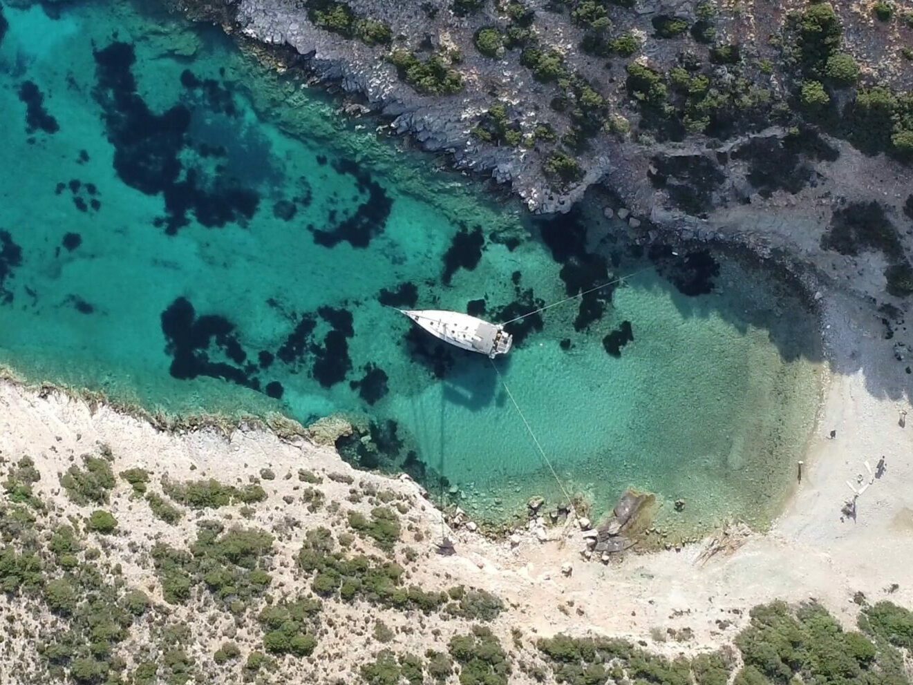 Prise de vue avec un drône du voilier Corto au mouillage dans une crique sur une île déserte dans les Cyclades